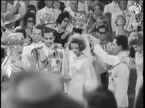 Crown Prince Harald of Norway and Prince Michael of Greece and Denmark hold crowns over the heads of the bride and groom
