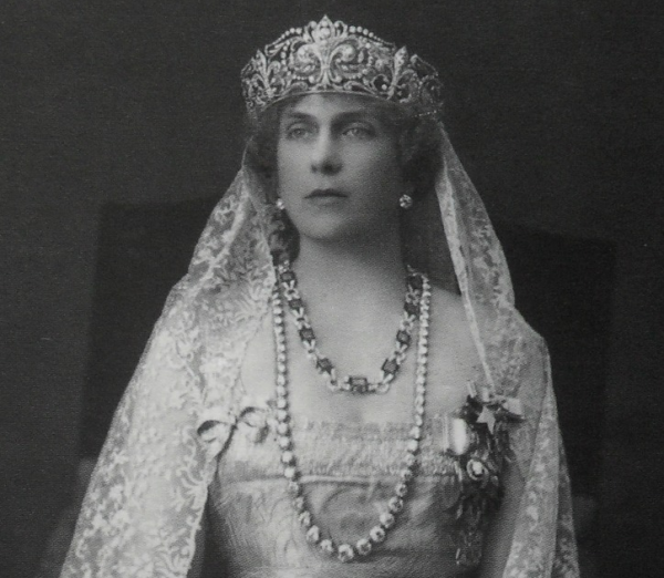 Queen Ena wears the earrings, tiara, and diamond necklace from the joyas de pasar collection, as well as her emerald necklace, in a formal portrait, ca. 1920s (Wikimedia Commons)