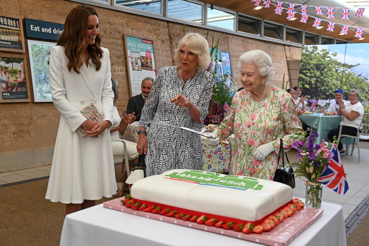 Queen Elizabeth II (C) considers cutting a cake with a sword, lent to her by The Lord-Lieutenant of Cornwall, Edward Bolitho, to celebrate of The Big Lunch initiative at The Eden Project during the G7 Summit on June 11, 2021 in St Austell, Cornwall, England
