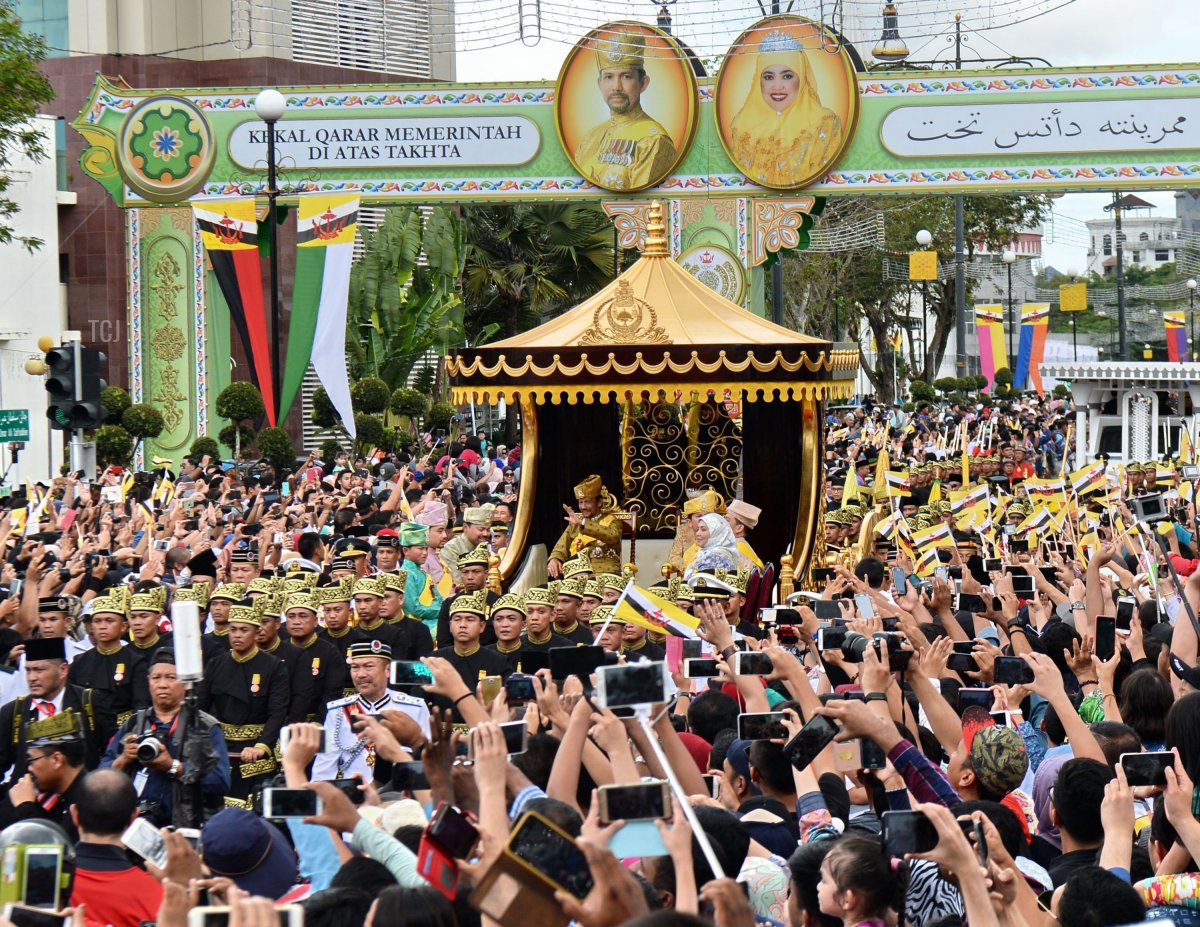 Brunei's Sultan Hassanal Bolkiah (center-L) and Queen Saleha (centre-R) wave from the royal chariot during a procession to mark his golden jubilee of accession to the throne in Bandar Seri Begawan on October 5, 2017