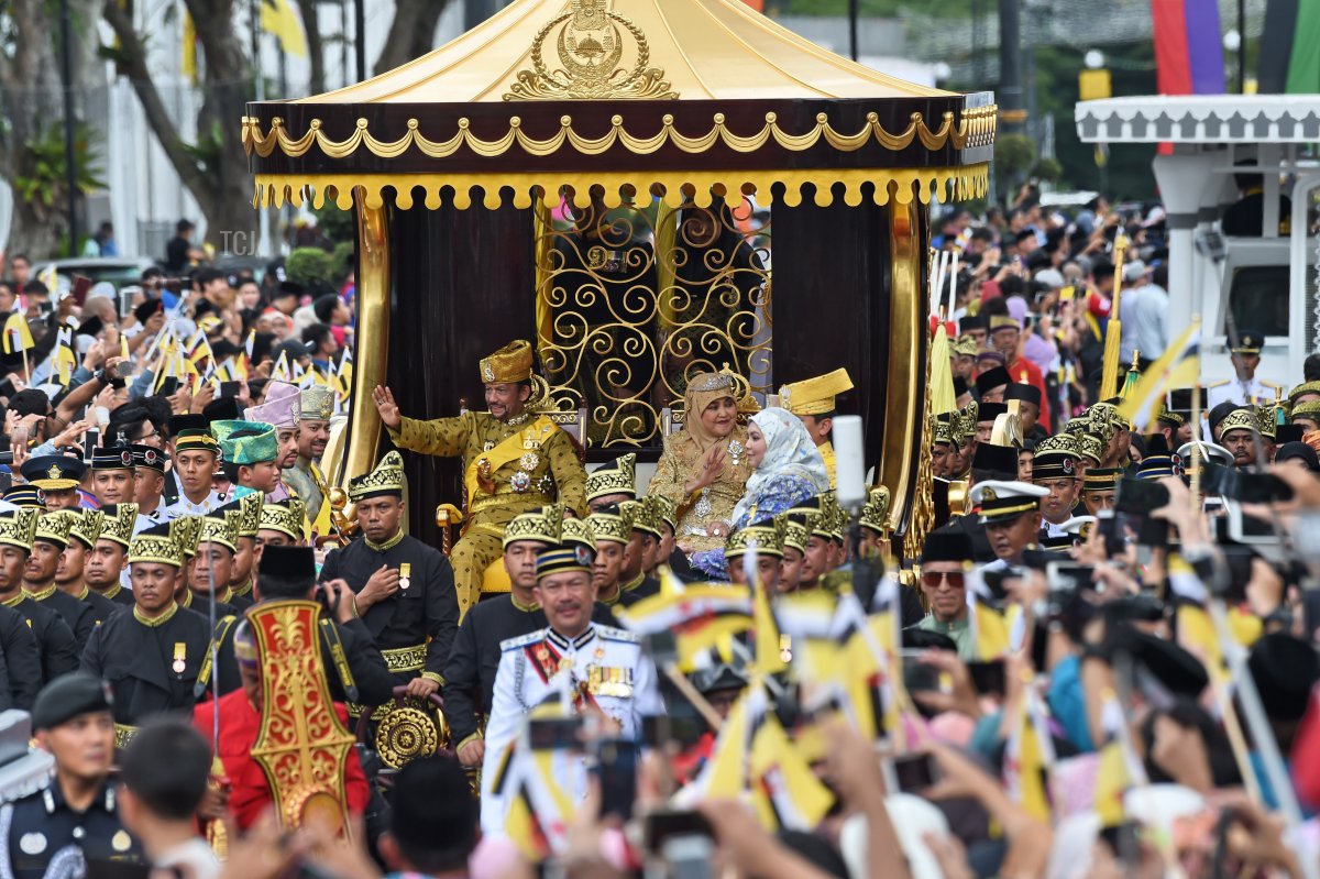 Brunei's Sultan Hassanal Bolkiah (center-L) and Queen Saleha (centre-R) wave from the royal chariot during a procession to mark his golden jubilee of accession to the throne in Bandar Seri Begawan on October 5, 2017