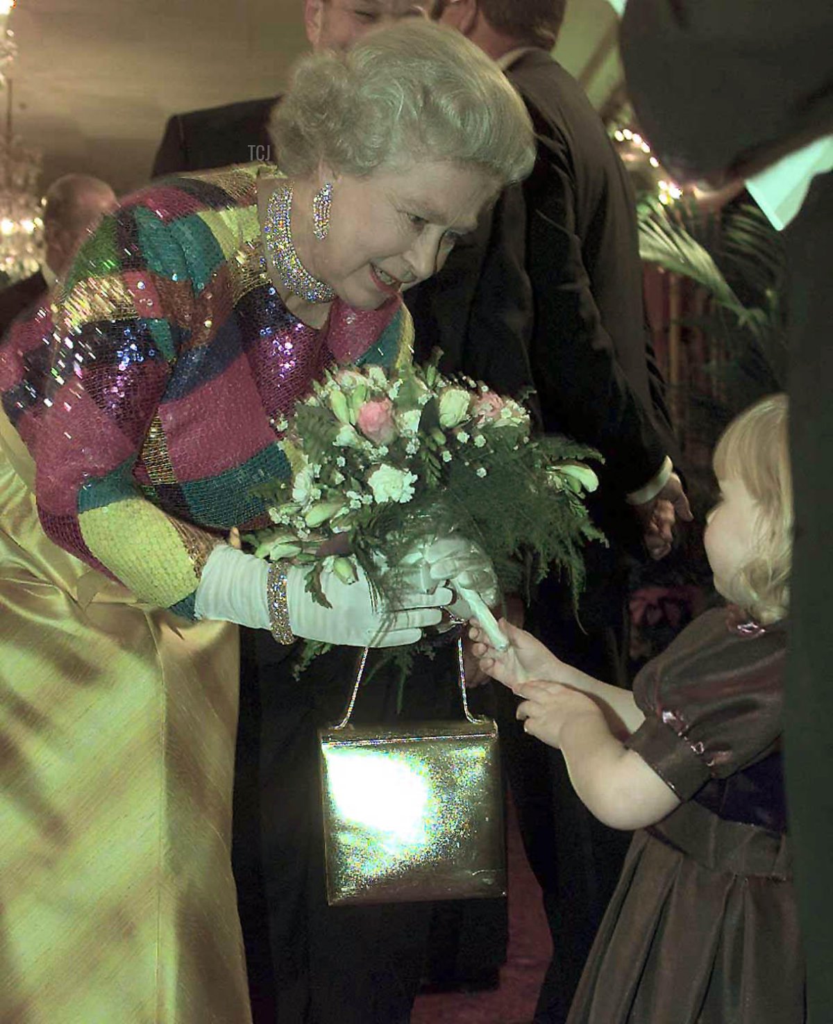 Britain's Queen Elizabeth II receives a bouquet from Lucy Molyneux aged 4 as she arrives at the Birmingham Hippodrome in Birmingham for the 1999 Royal Variety Performance