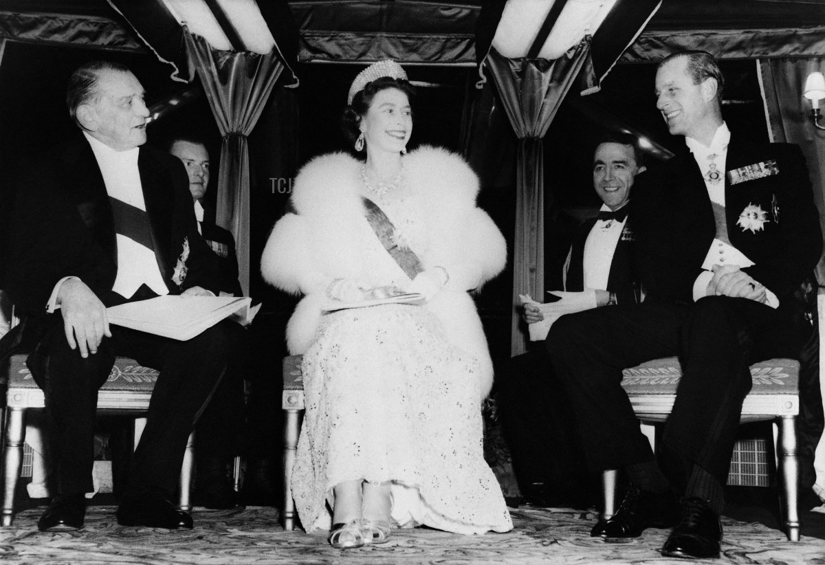 Queen Elizabeth II is flanked by French President Rene Coty and the Duke of Edinburgh aboard the "Borde Fretigny" in Paris during a state visit in France on April 10, 1957 (AFP via Getty Images)