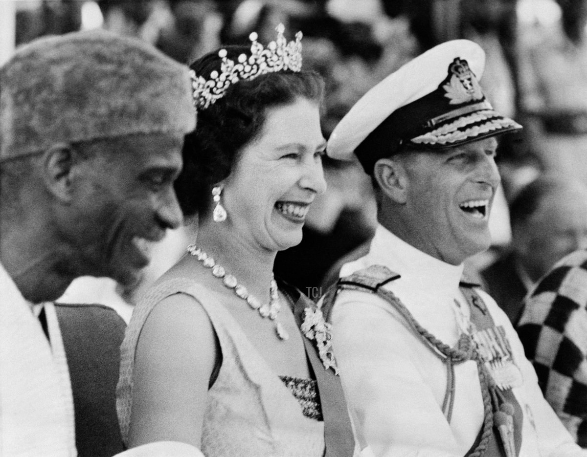 Britain's Queen Elizabeth II and Prince Philip, Duke of Edinburgh, laugh on December 4, 1961 as they watch the Susu dancers during their visit at the Northern Province of Sierra Leone