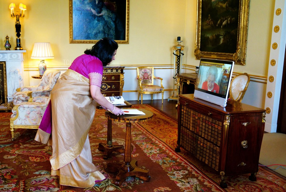 Britain's Queen Elizabeth II (R) appears on a screen via videolink from Windsor Castle, during a virtual audience to receive the High Commissioner of India to the United Kingdom, Gaitri Issar Kumar, at Buckingham Palace in London on March 8, 2022