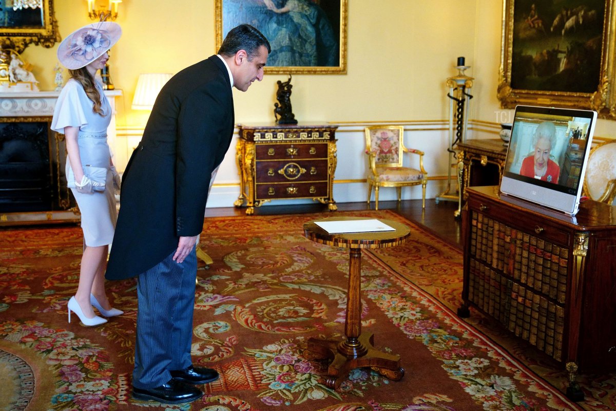 Britain's Queen Elizabeth II (R) appears on a screen via videolink from Windsor Castle, during a virtual audience to receive the Armenia's Ambassador to the United Kingsom, Varuzhan Nersesyan (C), and his wife Narine Malkhasyan, at Buckingham Palace in London on March 8, 2022