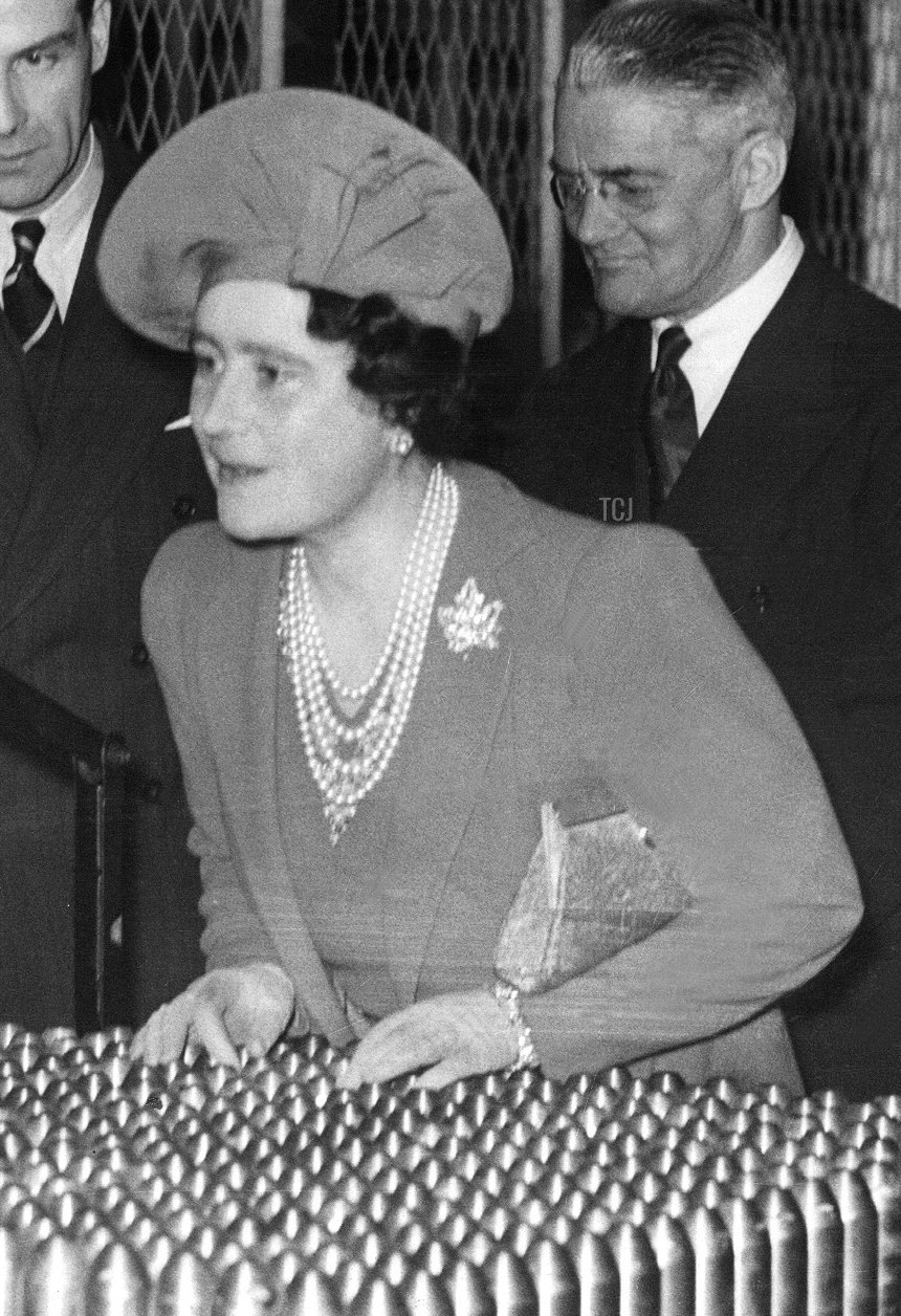 The King George VI (2nd-R) examines a tracer shell while his wife Queen Elizabeth (C) chats with a girl 18 April 1940 when they visit an ammunition factory somewhere in Midlands
