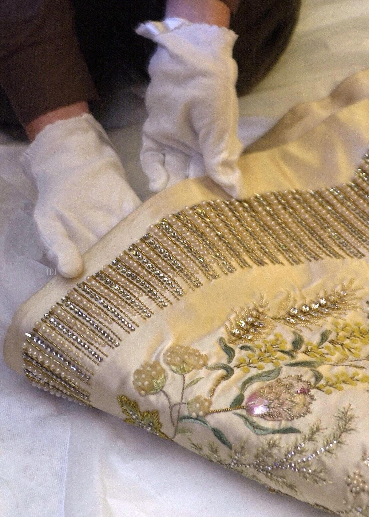 A conservator checks the Coronation Gown of Britain's Queen Elizabeth II at Windsor Castle , 06 October 2003, prior to it being exhibited along with her Robe of Estate