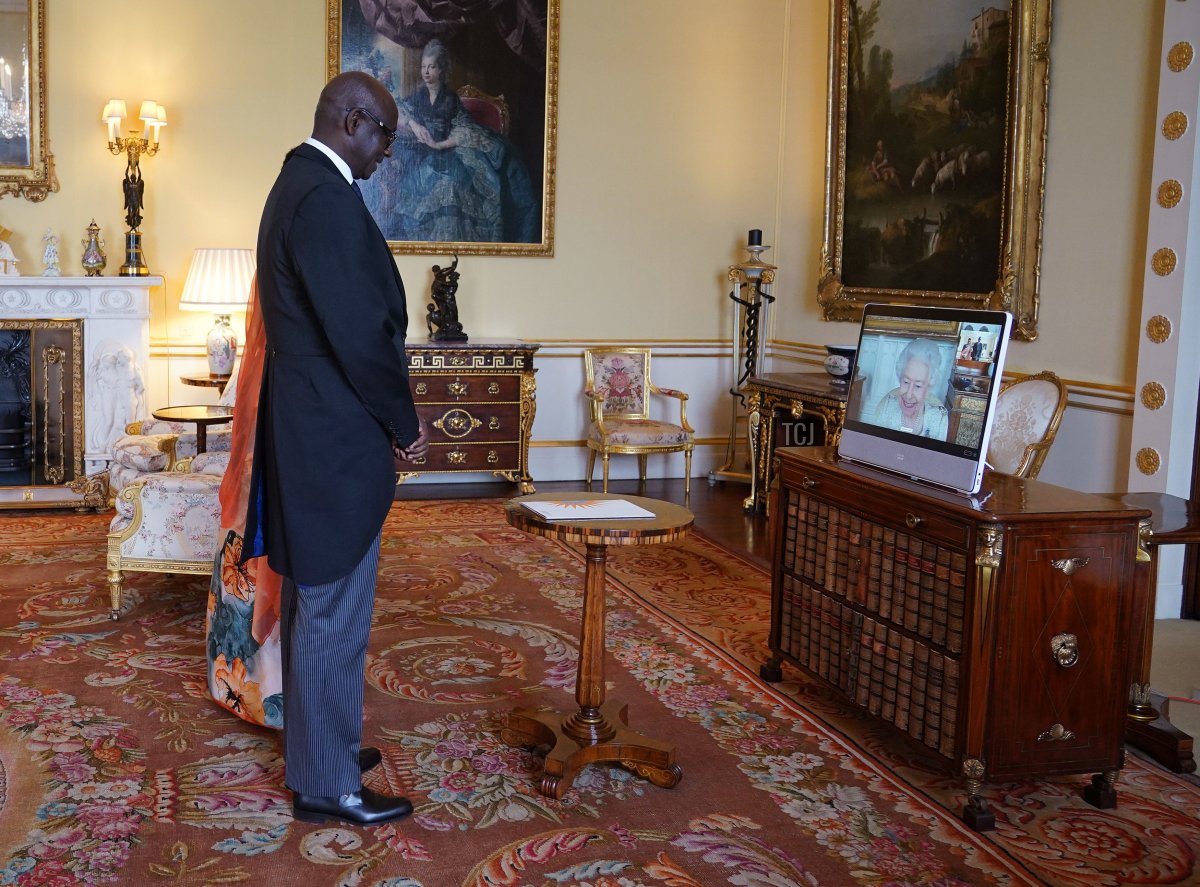 Queen Elizabeth II, in residence at Windsor Castle, appears on a screen via videolink, during a virtual audience to receive Johnston Busingye, High Commissioner for the Republic of Rwanda, and his wife Phoebe Murerwa, at Buckingham Palace on April 29, 2022 in London, England