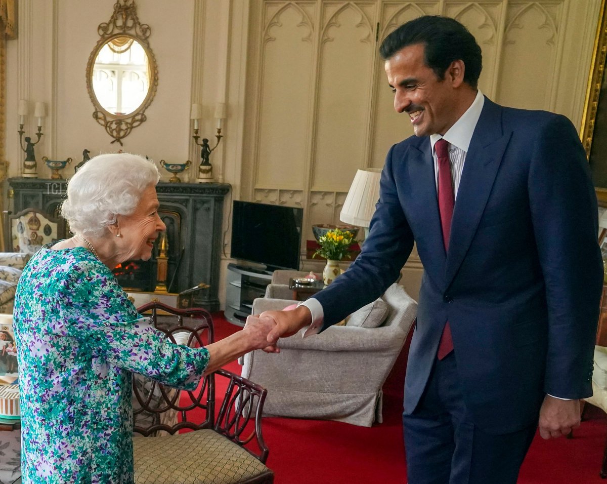 Britain's Queen Elizabeth II shakes hands with the Emir of Qatar Sheikh Tamim bin Hamad al-Thani during an audience at Windsor Castle, west of London on May 24, 2022