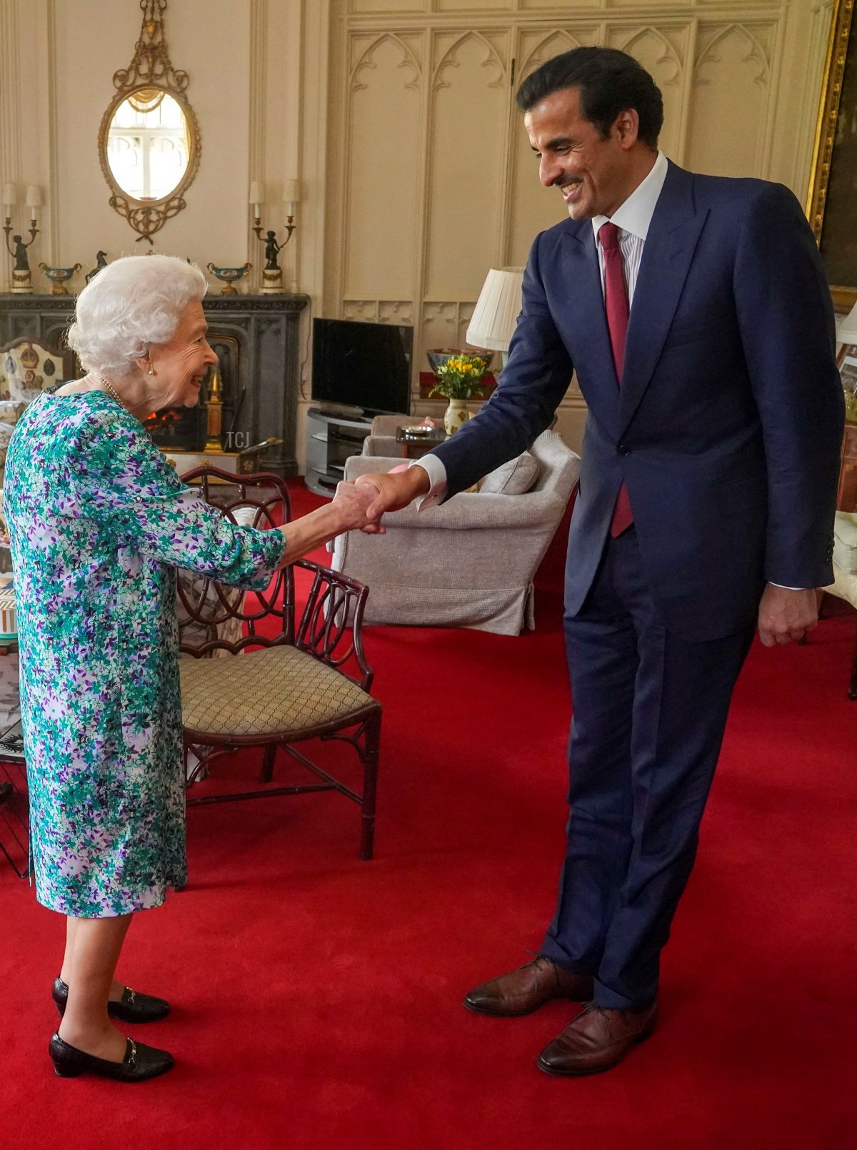 Britain's Queen Elizabeth II shakes hands with the Emir of Qatar Sheikh Tamim bin Hamad al-Thani during an audience at Windsor Castle, west of London on May 24, 2022