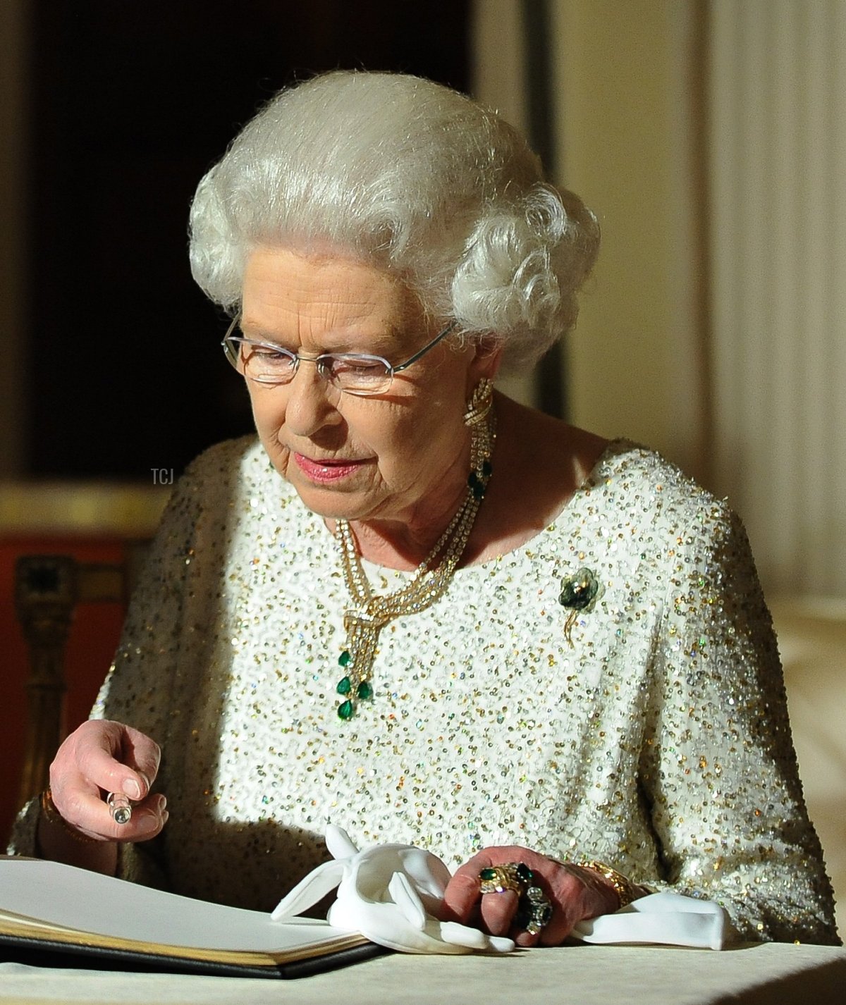 US President Barack Obama (L) looks on as Britain's Queen Elizabeth II signs a guest book after a reciprocal dinner at the Winfield House in London, on May 25, 2011