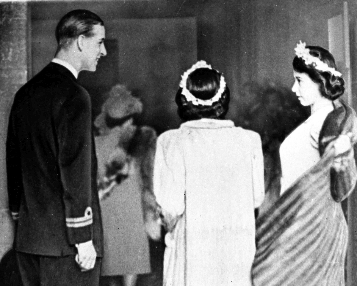 Prince Philip of Greece, later the Duke of Edinburgh, acts as an usher, assisting Princess Elizabeth, right, and Princess Margaret Rose, with their coats as they arrive at Romsey Abbey, Hampshire, December 23, 1946, for the wedding of Patricia Mountbatten