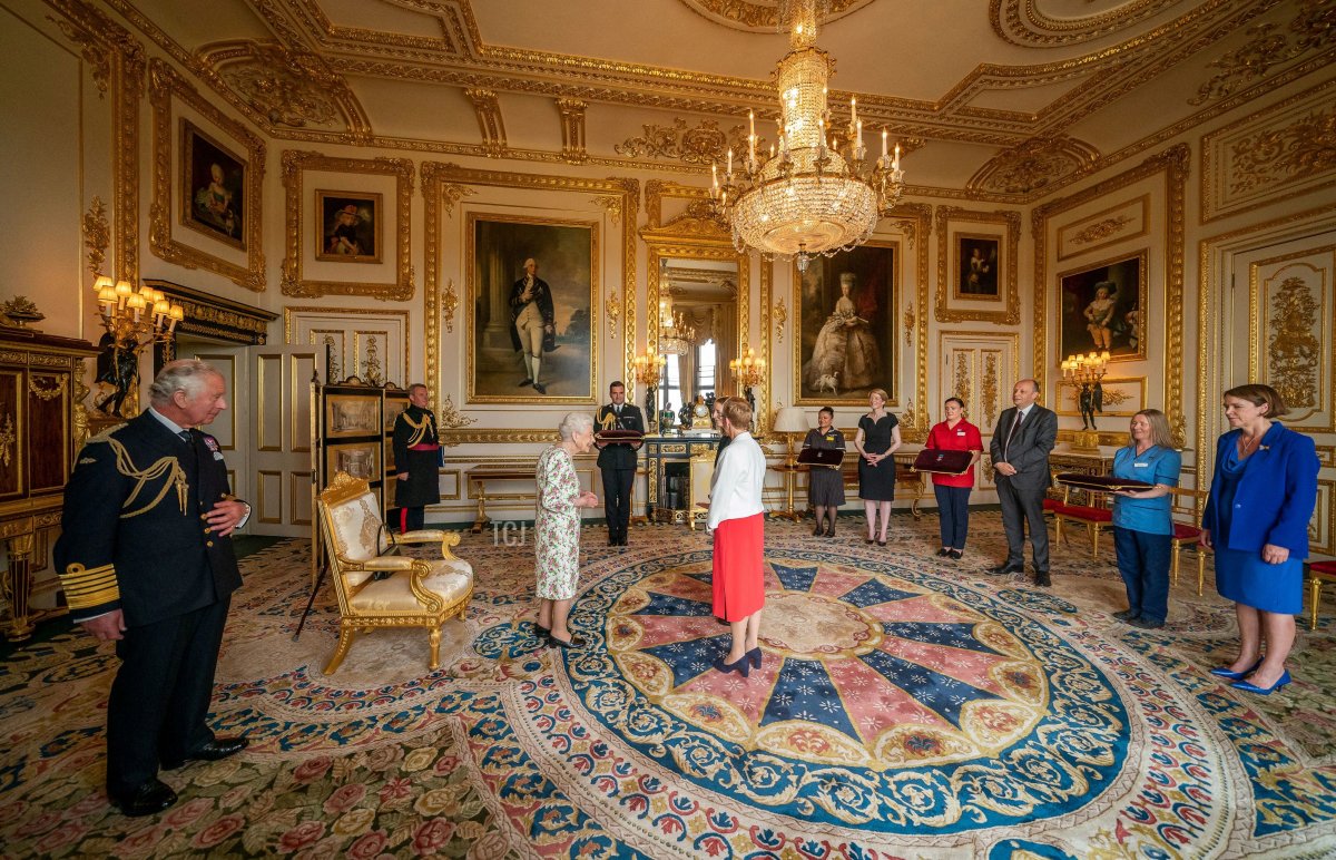 Britain's Prince Charles, Prince of Wales (L) watches Britain's Queen Elizabeth II present the George Cross to Judith Paget, Chief Executive NHS Wales and Dr Ami Jones, Intensive Care Consultant, Aneurin Bevan University Health Board, representatives of Britain's National Health Service (NHS), watched by other NHS workers, during an Audience at Windsor Castle, west of London on July 12, 2022