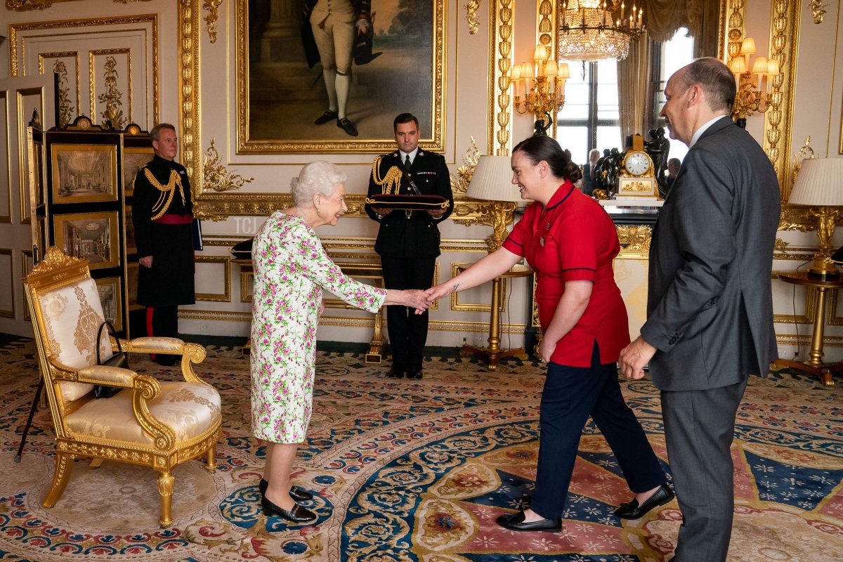 Britain's Queen Elizabeth II presents the George Cross to Peter May, Permanent Secretary at the Department of Health and Chief Executive of Health and Social care, and Sister Joanna Hogg, Royal Victoria Hospital Emergency Department, representatives of Britain's National Health Service (NHS), during an Audience at Windsor Castle, west of London on July 12, 2022