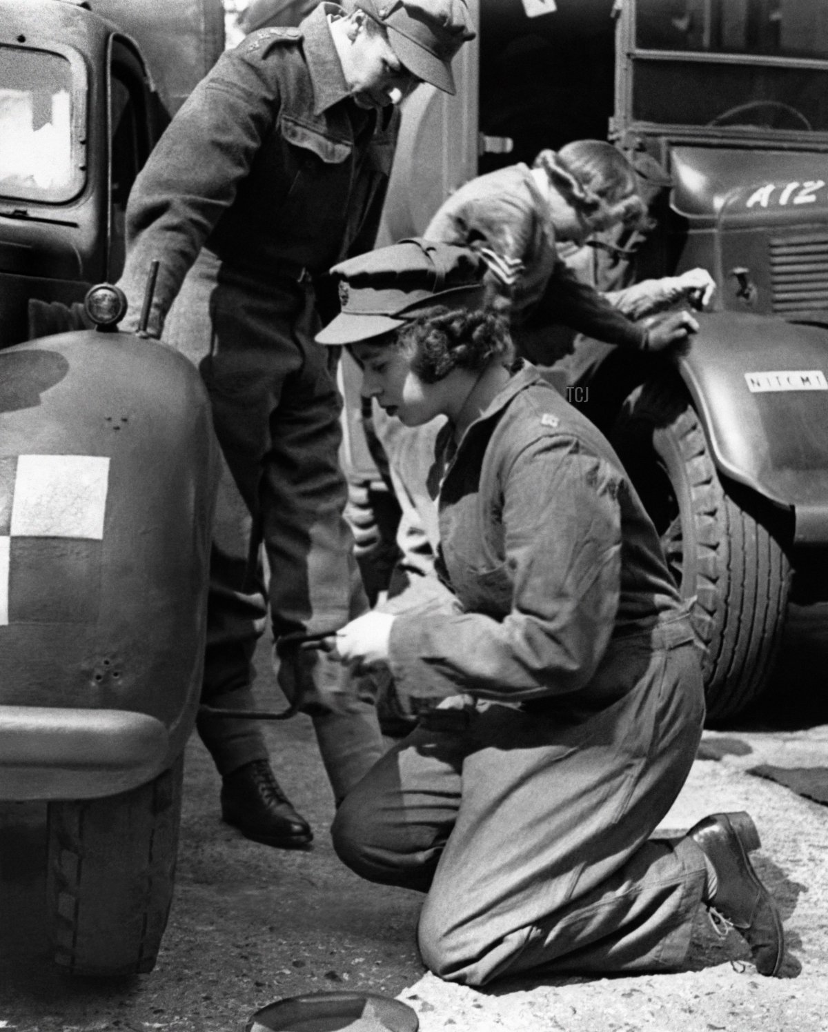 Princess Elizabeth changes the wheel of her car during training at an A.T.S training centre, in Southern England, in 1945