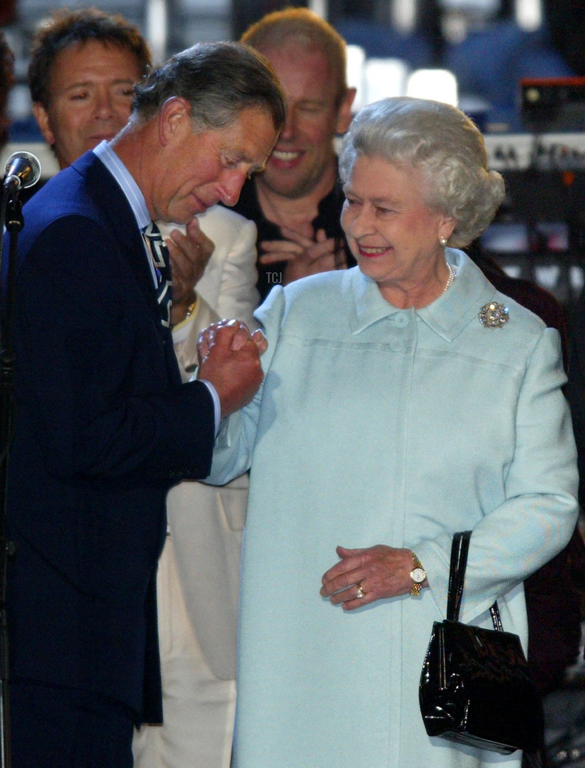 Prince Charles (L) kisses his mother Queen Elizabeth's hand after congratulating her on stage at the end of "Party at the Palace" in London 03 June 2002
