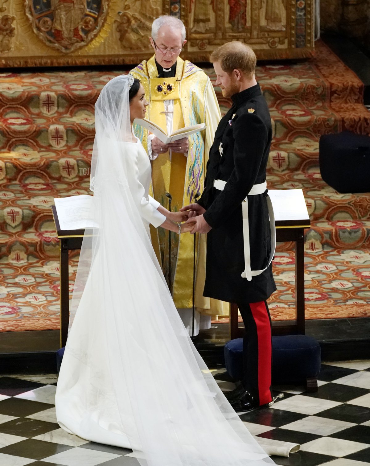 Britain's Prince Harry, Duke of Sussex (R) and US actress Meghan Markle (L) stand facing each other hand-in-hand before Archbishop of Canterbury Justin Welby (C) during their wedding ceremony in St George's Chapel, Windsor Castle, in Windsor, on May 19, 2018