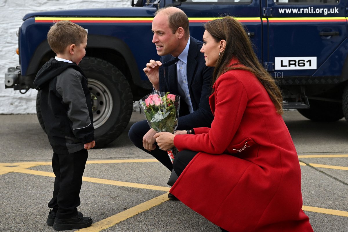 Britain's Prince William, Prince of Wales (C) gestures as his wife Britain's Catherine, Princess of Wales is presented with a posy of flowers by four-year-old Theo Crompton during their visit to the RNLI (Royal National Lifeboat Institution) Holyhead Lifeboat Station in Anglesey, north west Wales on September 27, 2022