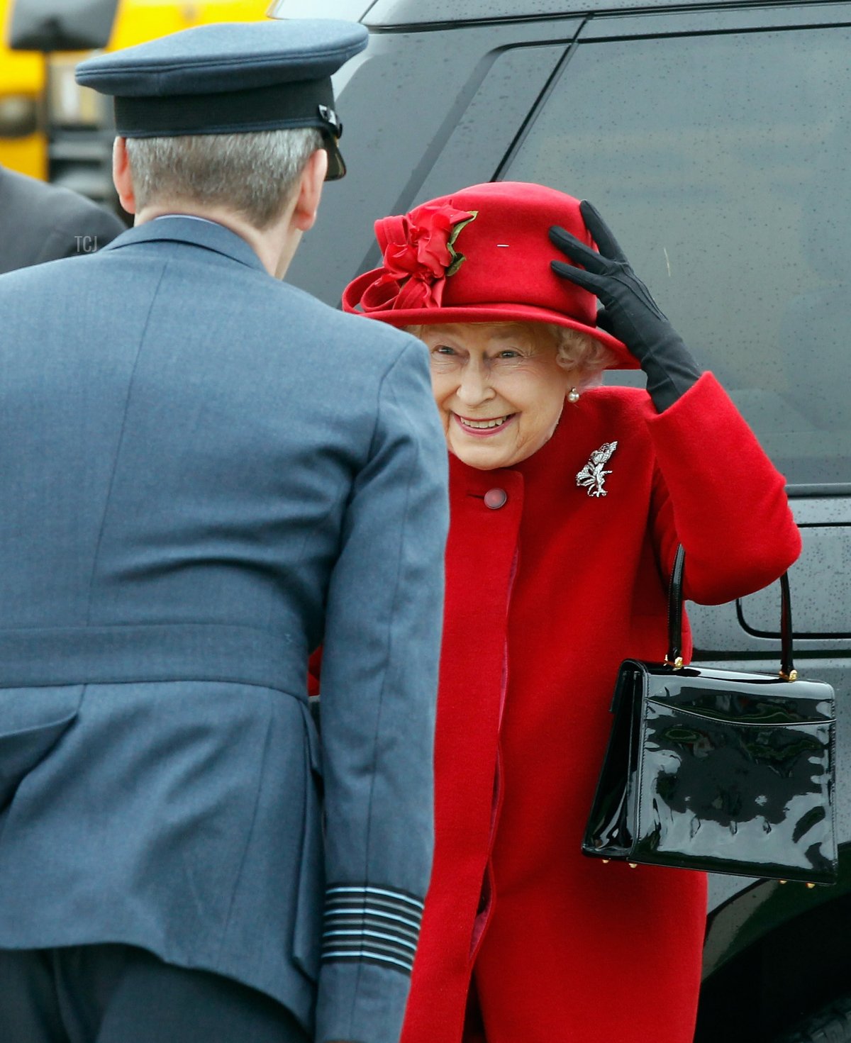 Queen Elizabeth II holds on to her hat in high winds as she tours RAF Valley where Prince William is stationed as a search and rescue helicopter pilot on April 1, 2011 in Holyhead, United Kingdom