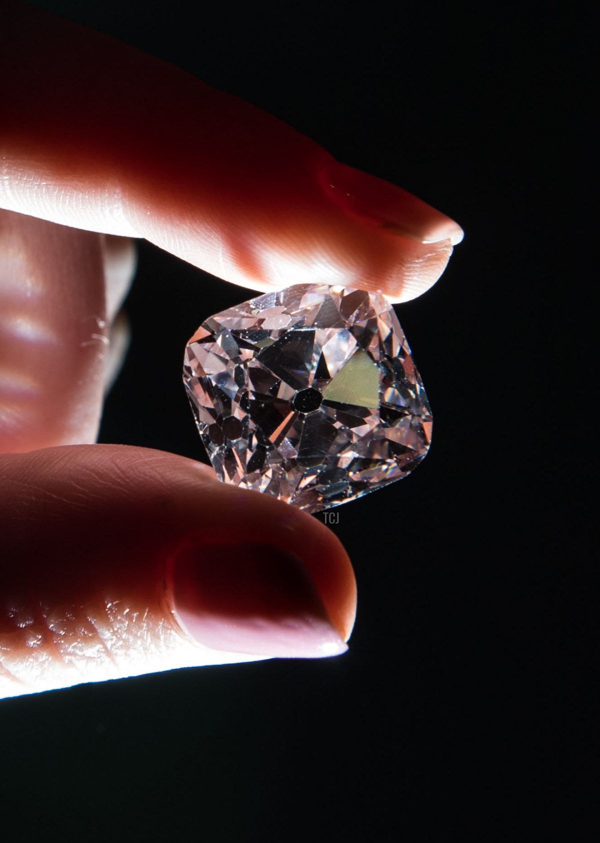 A woman poses with the 'Le Grand Mazarin', a 19.07 carat pink diamond, at Christie's auction house in London on October 17, 2017