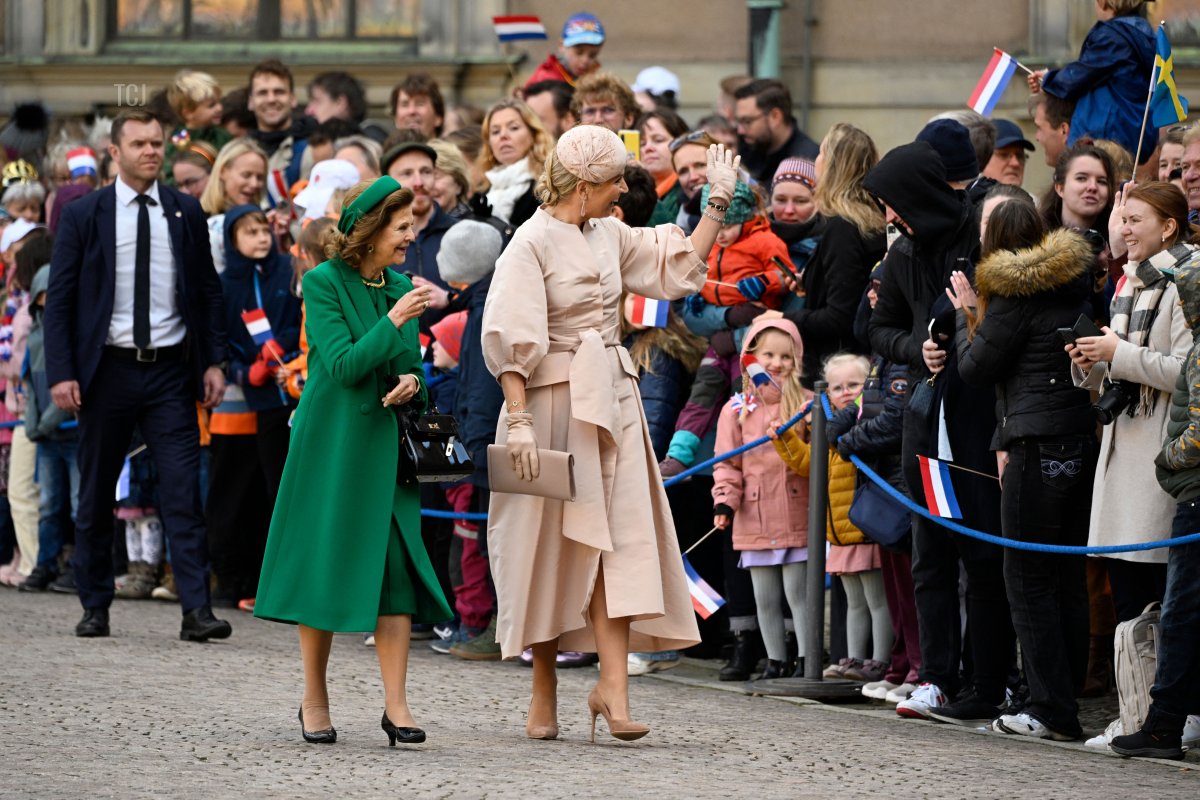 Queen Silvia of Sweden (L) and Queen Maxima of the Netherlands wave to waves to well-wishers during a welcoming ceremony at the Royal Palace in Stockholm, on October 11, 2022