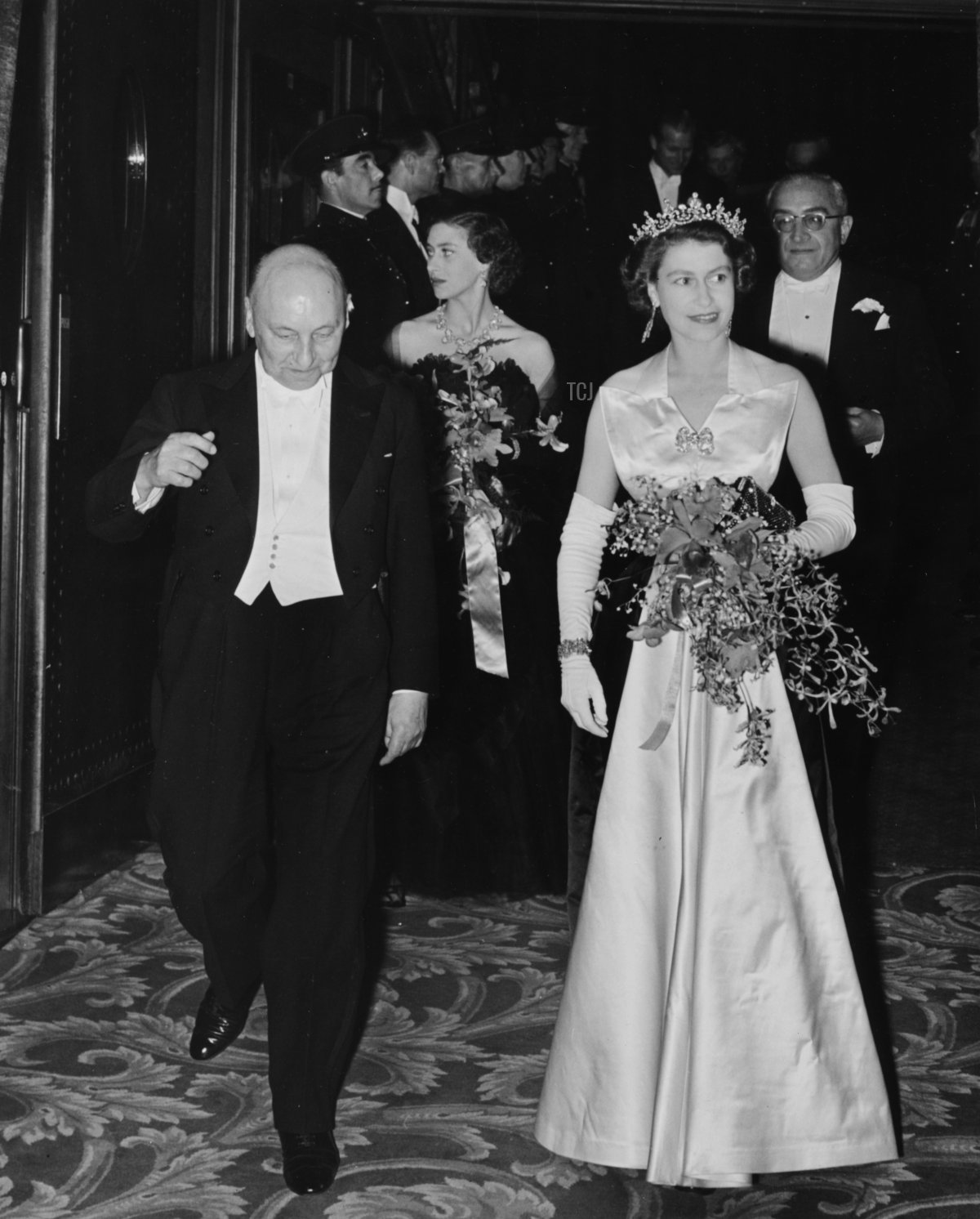 Queen Elizabeth II is escorted by Reginald Bromhead, the Chairman of the Cinematograph and Trade Benevolent Fund, as she and Princess Margaret (behind) leave the Royal Film Performance in Leicester Square, London, October 27th 1952