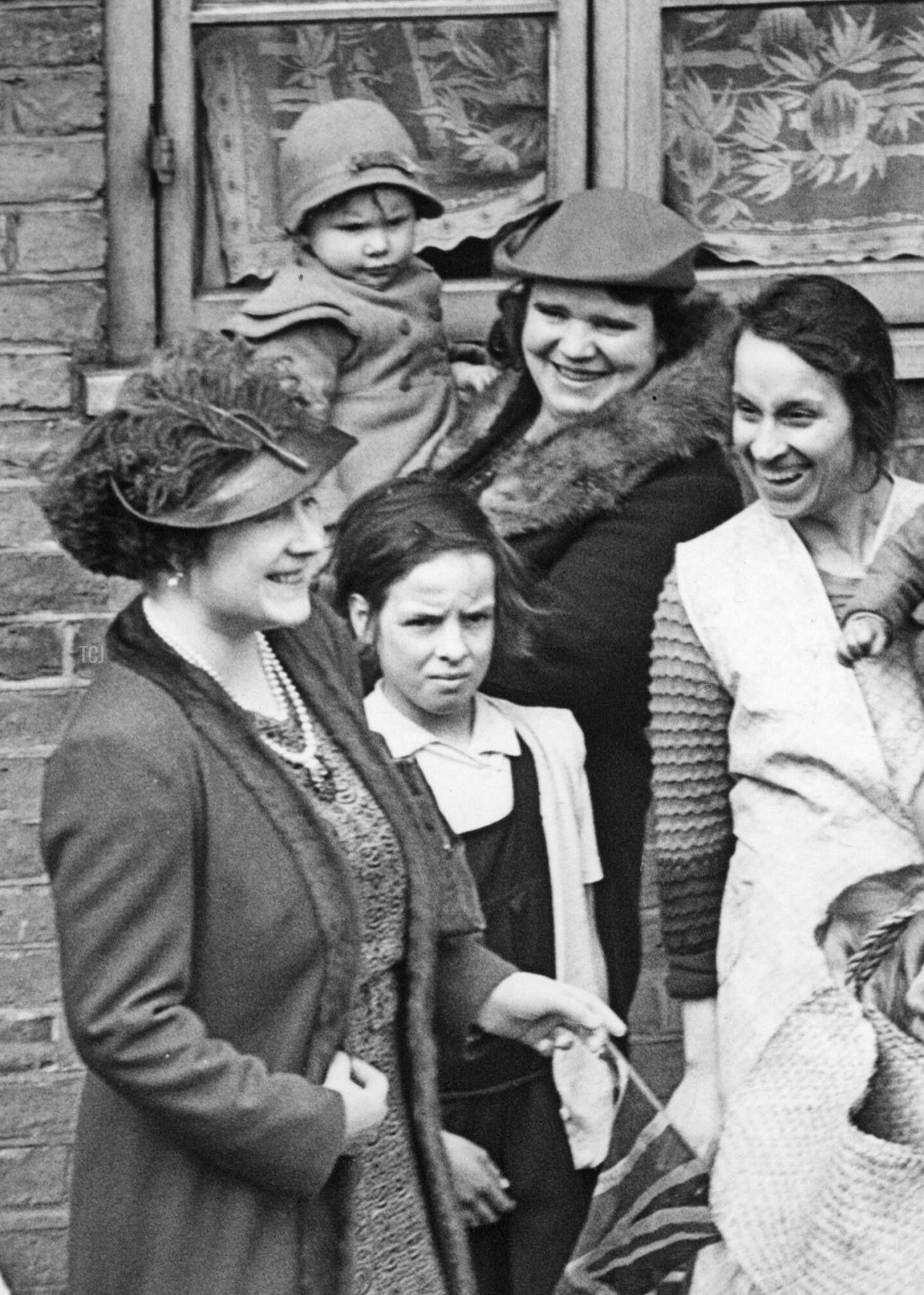King George VI and Queen Elizabeth in London, 1938. King George VI (2nd from left) and Queen Elizabeth (3rd from left) visit the poorer districts in South London. Here in conversation with the residents of the McManus House in Battersea. Date created: 16/03/1938