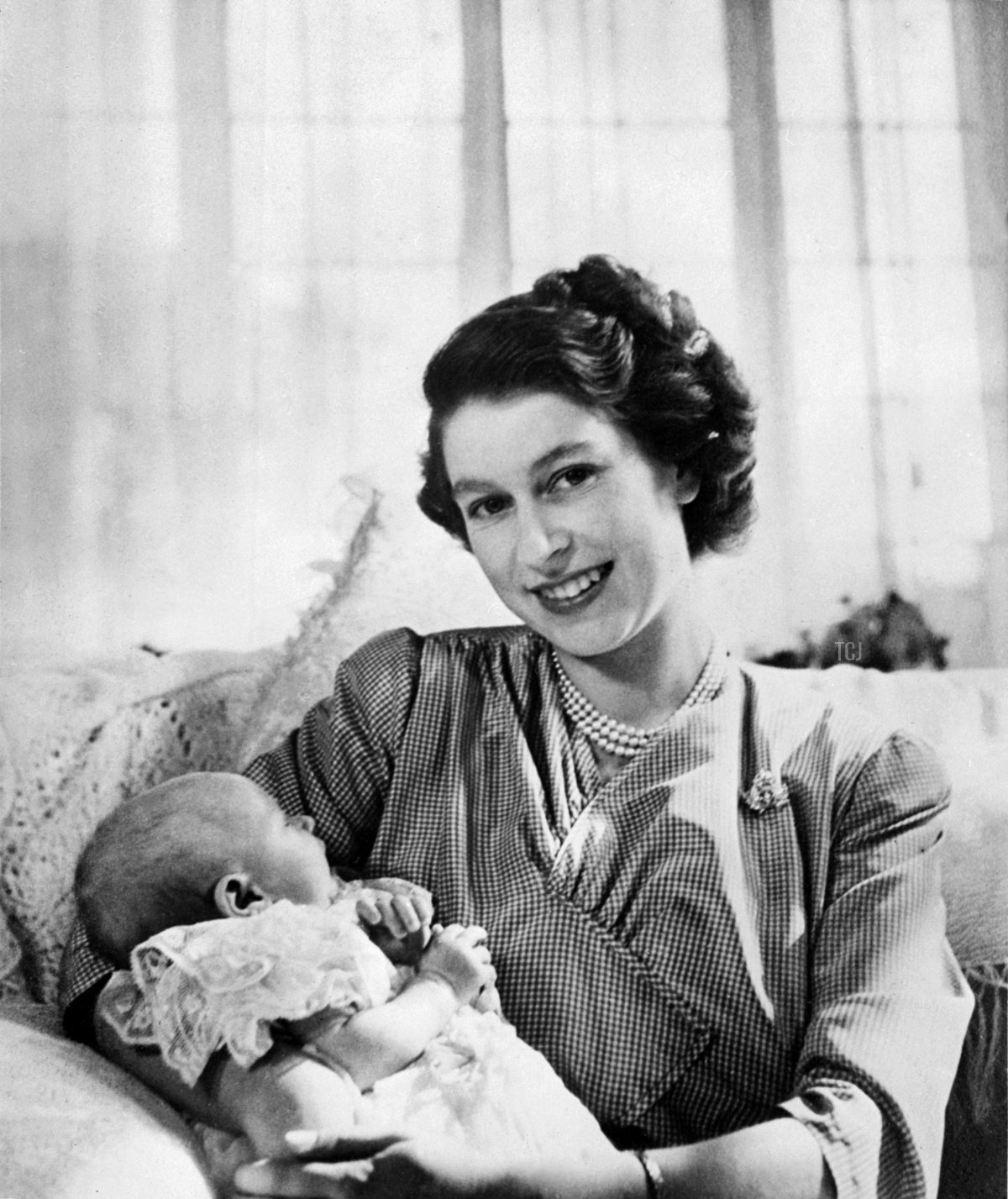 Britain's Princess Elizabeth smiles as she is holding on her lap Princess Anne, born 18 August 1950