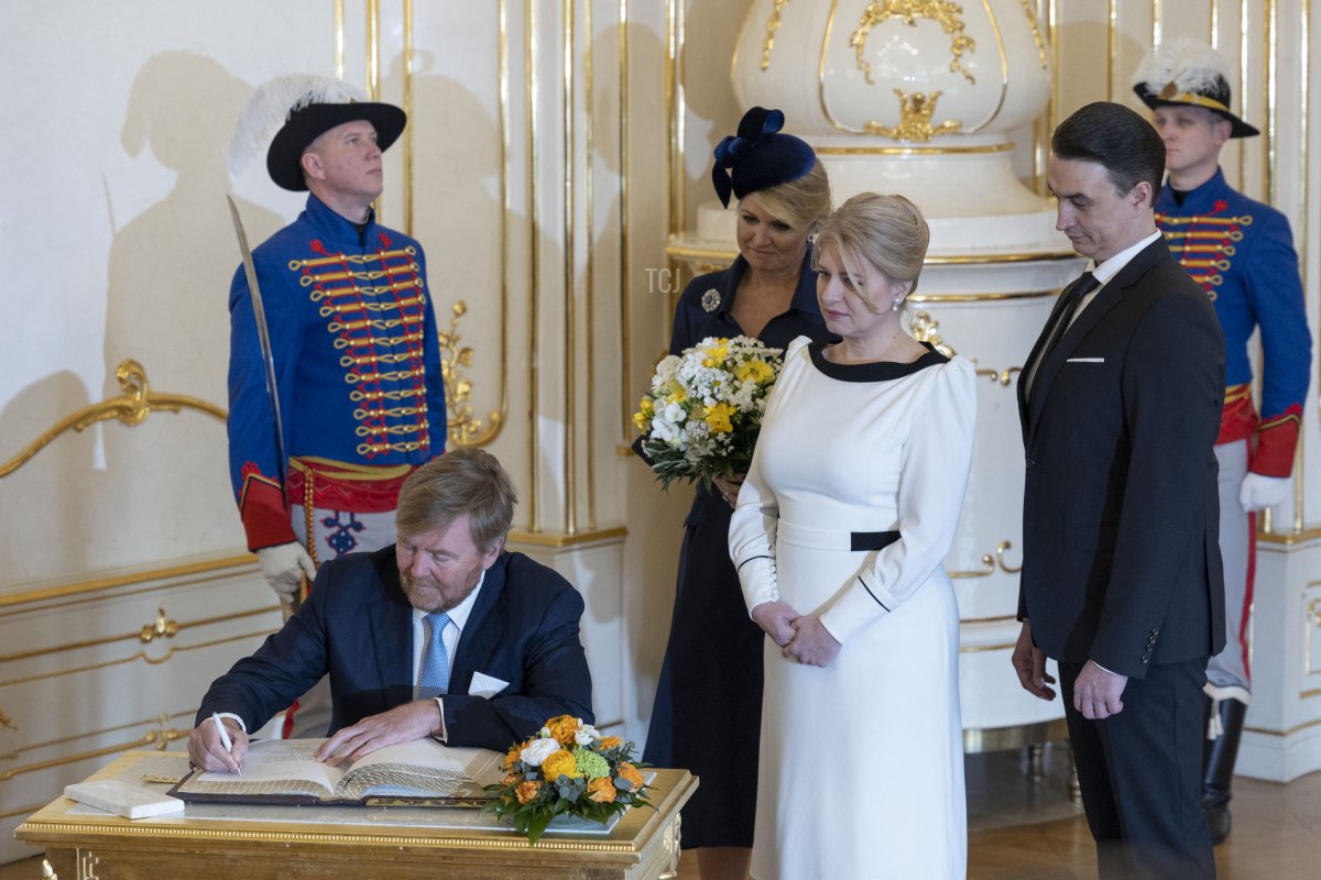 King Willem-Alexander of the Netherlands signs a guest book as Queen Maxima of the Netherlands, President Zuzana Caputova of Slovakia, and her partner, Juraj Rizman, look on during a welcome ceremony at the Presidential Palace in Bratislava on March 7, 2023 (TOMAS BENEDIKOVIC/AFP via Getty Images)