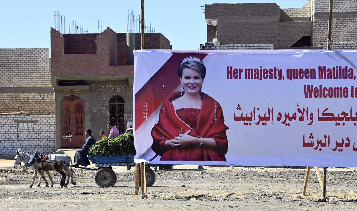 A large poster saying 'Her majesty, Queen Matilda of Belgium & Princess Elizabeth Welcome to Deir El Bersha' and a horse pulling a carriage are pictured on the excavation site of Dayr-al-Barsha in Egypt, March 16, 2023 (ERIC LALMAND/BELGA MAG/AFP via Getty Images)