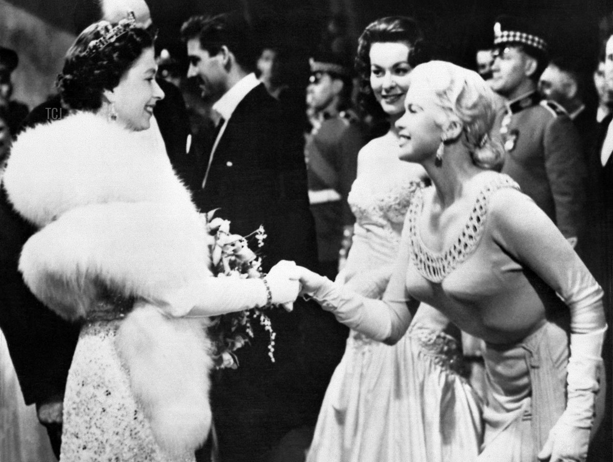 Queen Elizabeth II meets actress Jayne Mansfield she attends the Royal Film Performance of Les Girls at the Odeon Theatre in Leicester Square, London, November 4, 1957 (INTERNATIONAL NEWS PHOTOS/AFP via Getty Images)