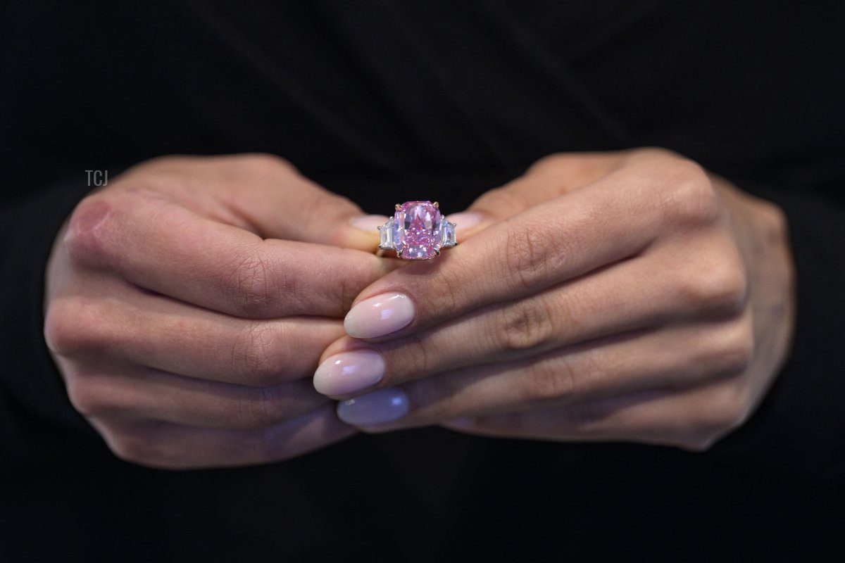A model holds a 10.57 carat vivid pink diamond, with an estimated value of more than $35 million US dollars, during a press preview at Sotheby's in New York City on March 27, 2023 (ANGELA WEISS/AFP via Getty Images)