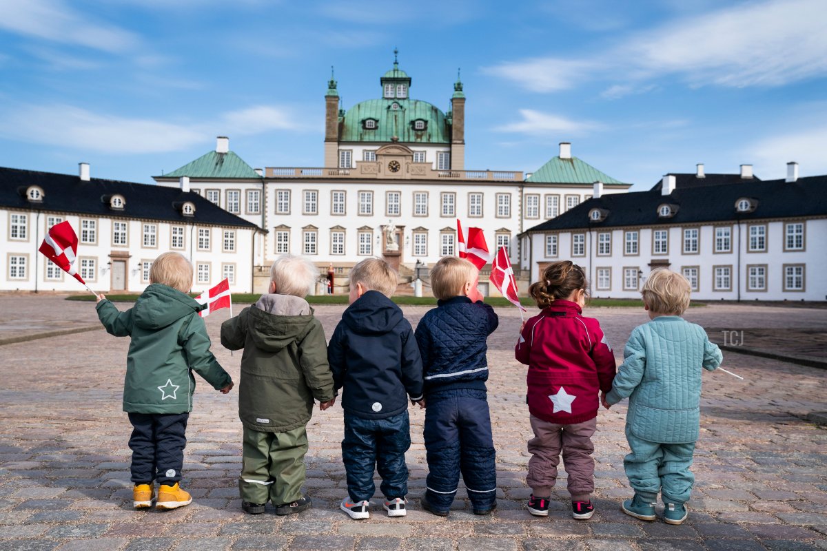 Children wave Danish flags in front of Fredensborg Palace in Fredensborg, Denmark, on April 16, 2021, the 81st birthday of Queen Margrethe II of Denmark, which she is celebrating in private due to the ongoing coronavirus pandemic (MARTIN SYLVEST/Ritzau Scanpix/AFP via Getty Images)