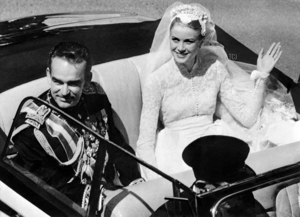 Prince Rainier III and Princess Grace of Monaco salute the crowd as they leave Saint Nicholas Cathedral in a convertible cream and black Rolls Royce, offered by the people of Monaco as a wedding gift, after their wedding ceremony in Monaco on April 19, 1956 (AFP via Getty Images)