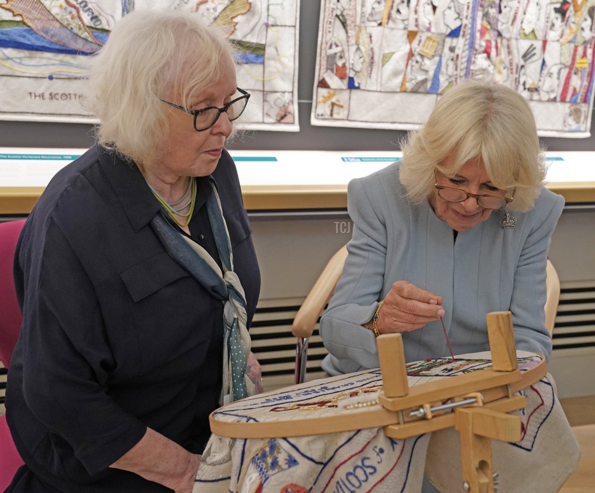 Great Tapestry of Scotland stitcher coordinator Dorie Wilke watches Queen Camilla work on a commemorative tapestry during her visit to The Great Tapestry of Scotland visitor center in Galashiels, in the Scottish Borders, on July 6, 2023 (Andrew Milligan - Pool/Getty Images)