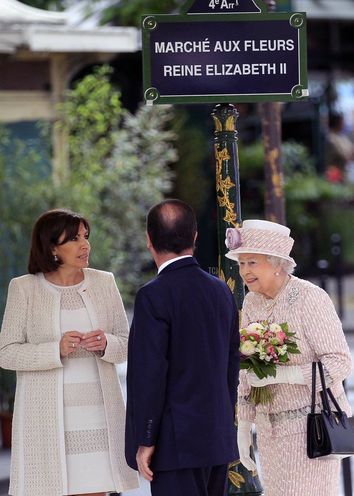 Queen Elizabeth II of the United Kingdom, with French President Francois Hollande and Paris Mayor Anne Hidalgo, unveils a plaque during a ceremony for the renaming of the Queen Elizabeth II Flower Market in Paris on June 7, 2014 (Thierry Chesnot/Getty Images)