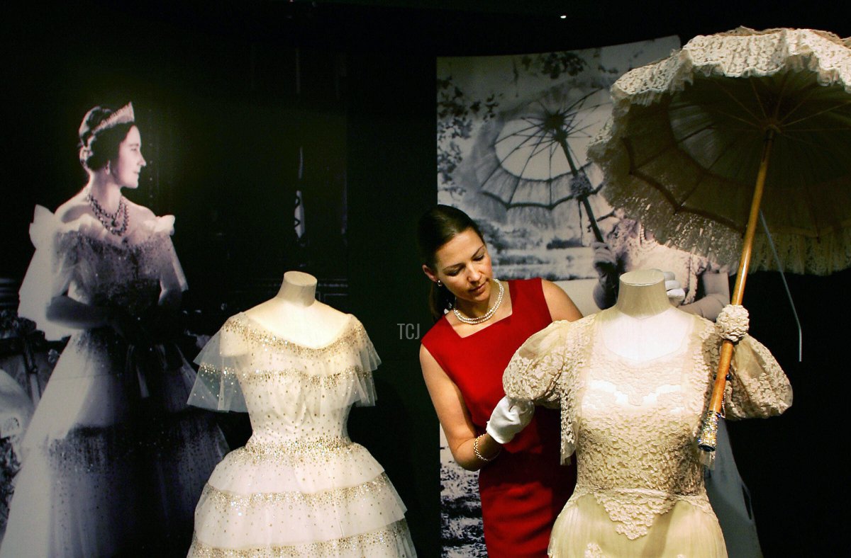 Caroline de Guitaut of the Royal Collection Trust adjusts a day dress at the preview of an exhibition of Queen Elizabeth's White Wardrobe at Buckingham Palace in London on July 29, 2005 (ADRIAN DENNIS/AFP via Getty Images)