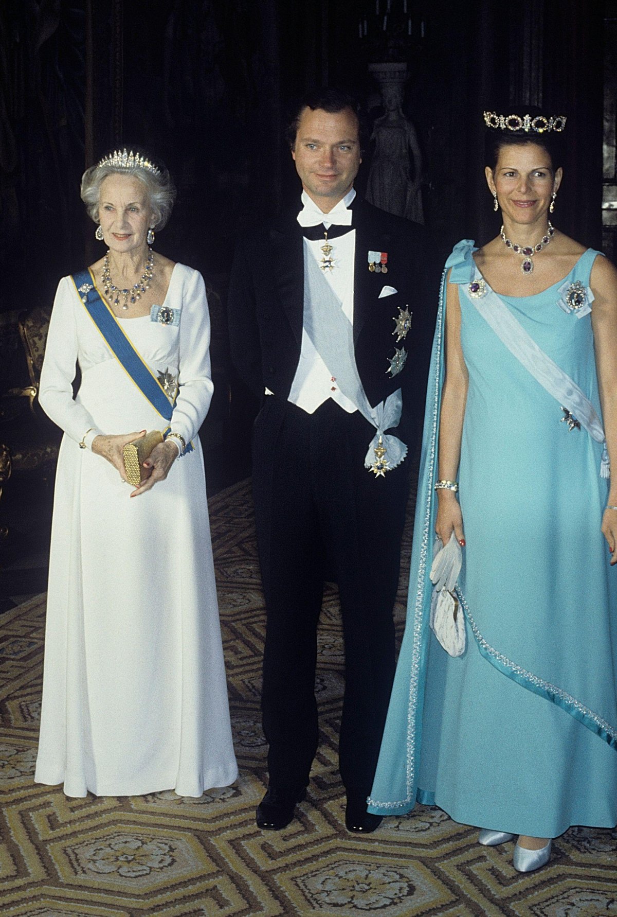 King Carl XVI Gustaf and Queen Silvia of Sweden, with Princess Lilian, attend a gala dinner at the Royal Palace in Stockholm, February 1982 (Classic Picture Library/Alamy)