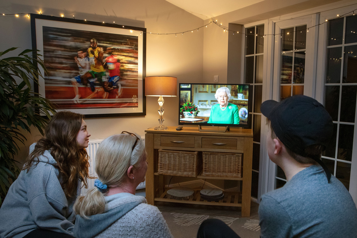 A family in the village of Hartley Wintney watches Queen Elizabeth II's special address to the nation regarding the pandemic on television on April 5, 2020 (ADRIAN DENNIS/AFP via Getty Images)