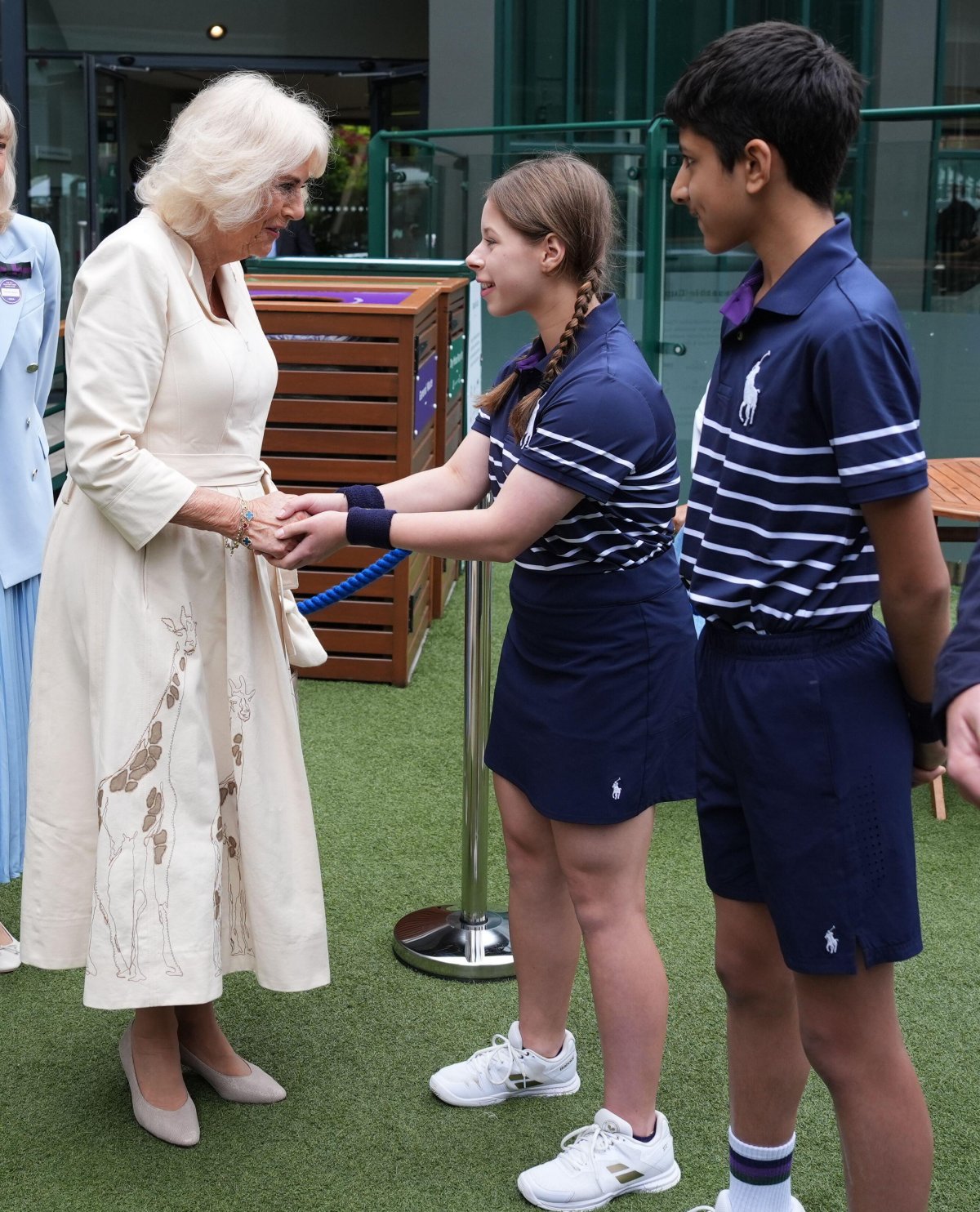 Queen Camilla meets Natalia from Burntwood School in Wandsworth and Yug from Harris Academy Wimbledon at the All England Lawn Tennis and Croquet Club on July 10, 2024 (Jordan Pettitt/PA Images/Alamy)