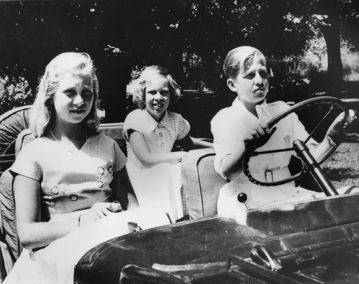 King Constantine II of the Hellenes with his sisters, Queen Sofia of Spain and Princess Irene of Greece and Denmark, are pictured in a car as children, ca. 1955 (Central Press/Hulton Archive/Getty Images)