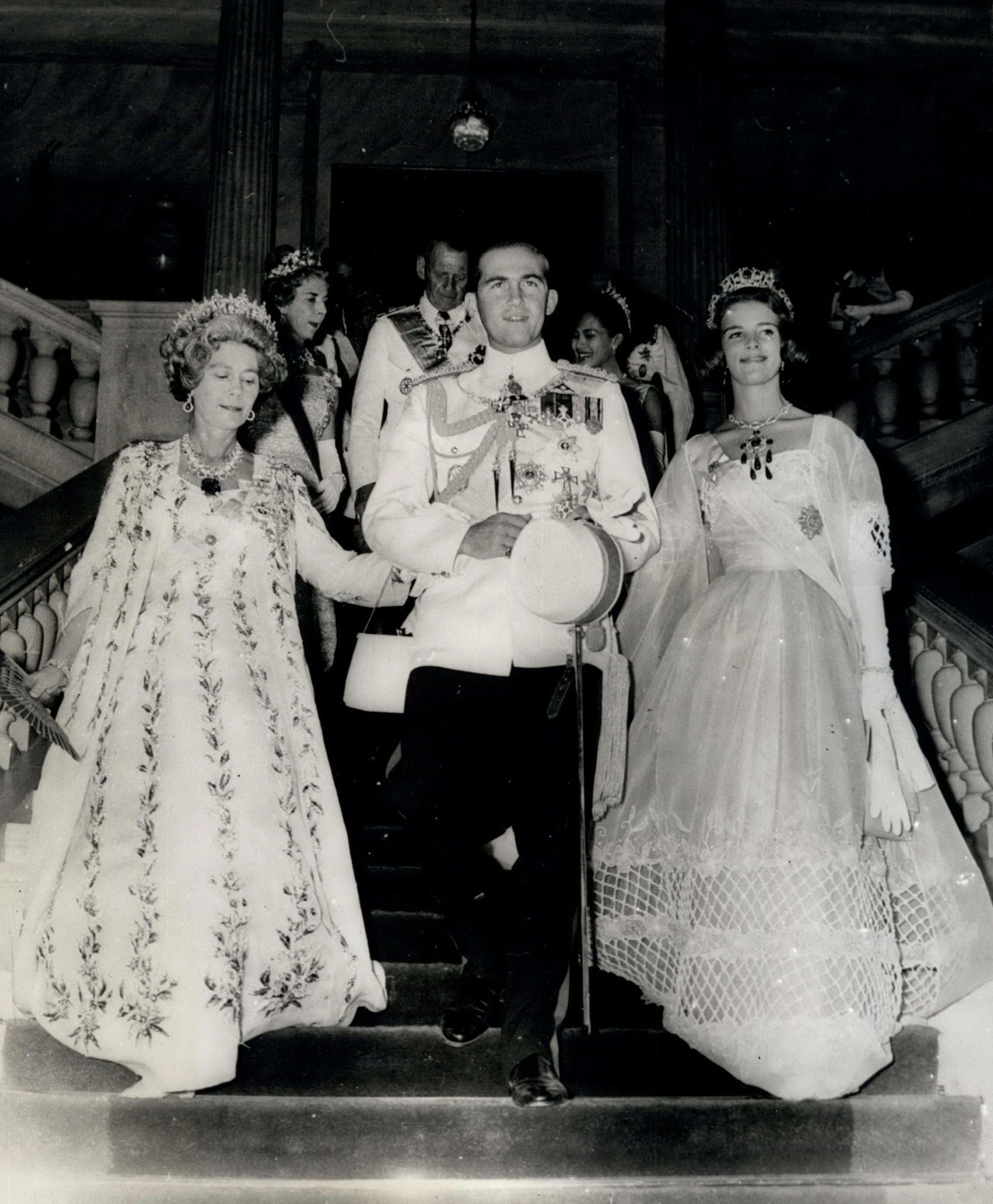 King Constantine II of the Hellenes arrives with his mother, Queen Friederike, and his fiancée, Princess Anne-Marie of Denmark, for a ball held on the night before the royal wedding, September 17, 1964 (Keystone Press/Alamy)