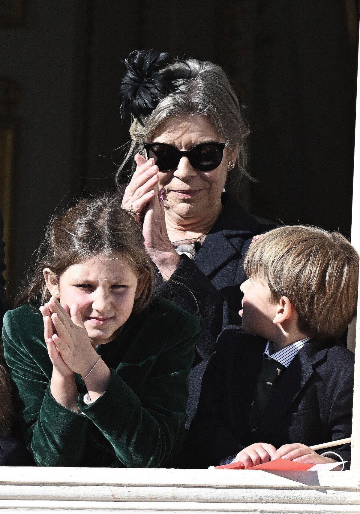 The Princess of Hanover, with two of her grandchildren, watches a military ceremony from a palace balcony during the celebrations of Monaco's National Day on November 19, 2024 (David Niviere/Abaca Press/Alamy)
