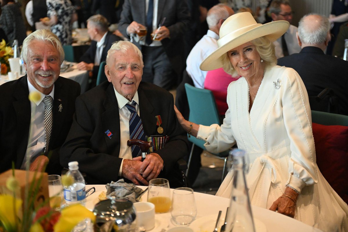 Queen Camilla speaks with Bob Gelder and his eldest son, Kim, during a reception for VJ veterans and their families hosted by the Royal British Legion in Staffordshire on August 15, 2025 (Eddie Mulholland/PA Images/Alamy)