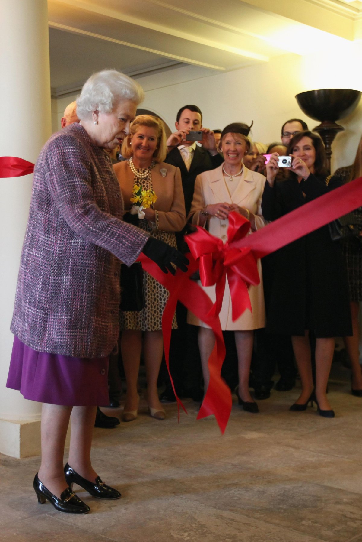 Queen Elizabeth II pulls a ribbon during a ceremony marking the official reopening of Kensington Palace in London on March 14, 2012 (Dan Kitwood/PA Images/Alamy)